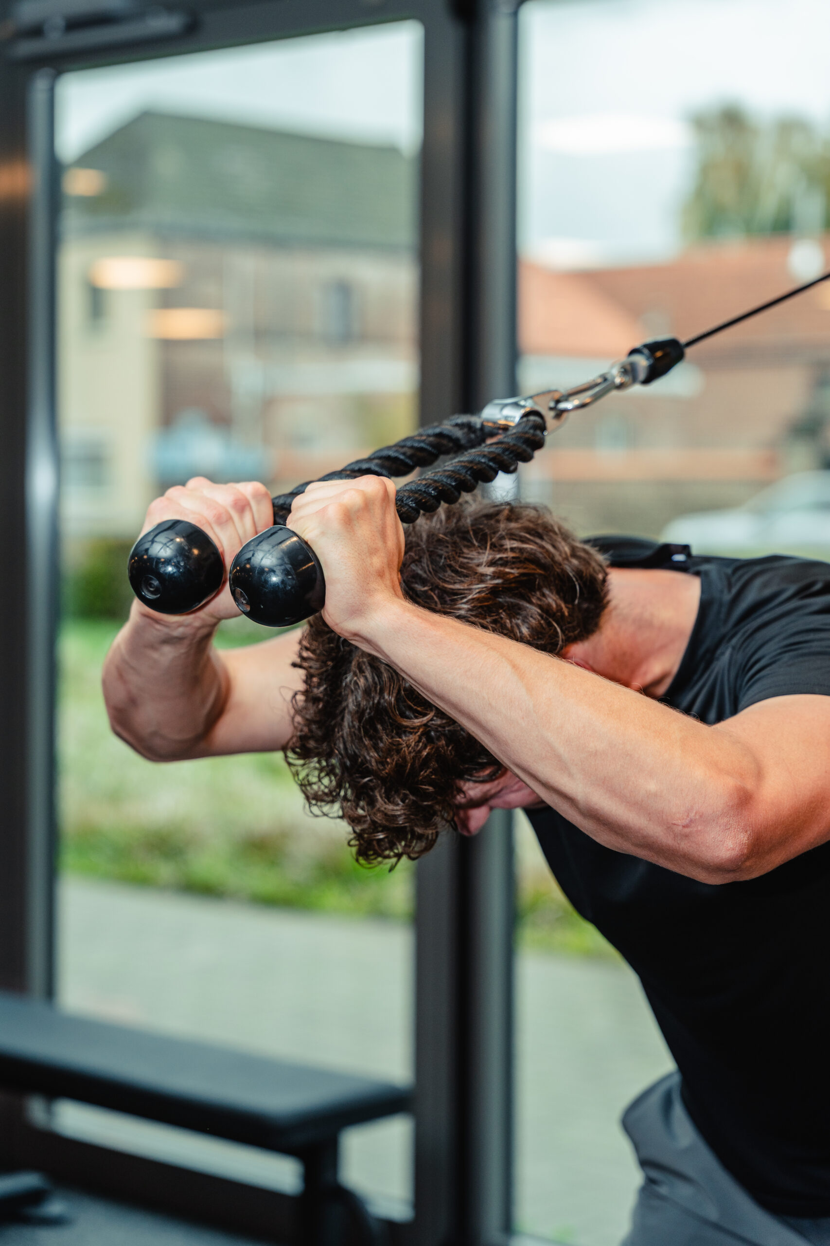 Man voert tricep rope pushdown oefening uit in de fitnessruimte
