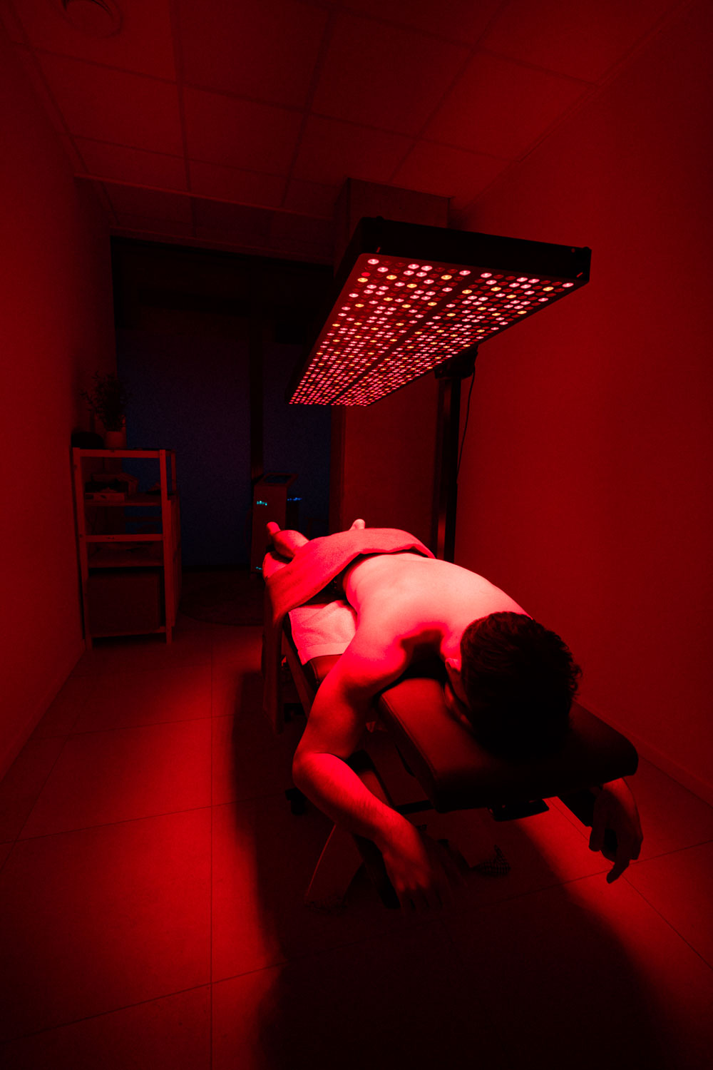 Cliënt ligt onder rood licht therapie lamp tijdens recovery sessie