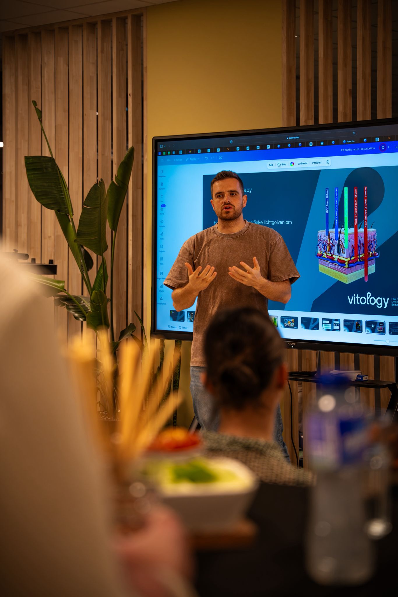 Xander De Nys geeft een presentatie over IHHT en red light therapy voor een publiek, met microfoon in de hand